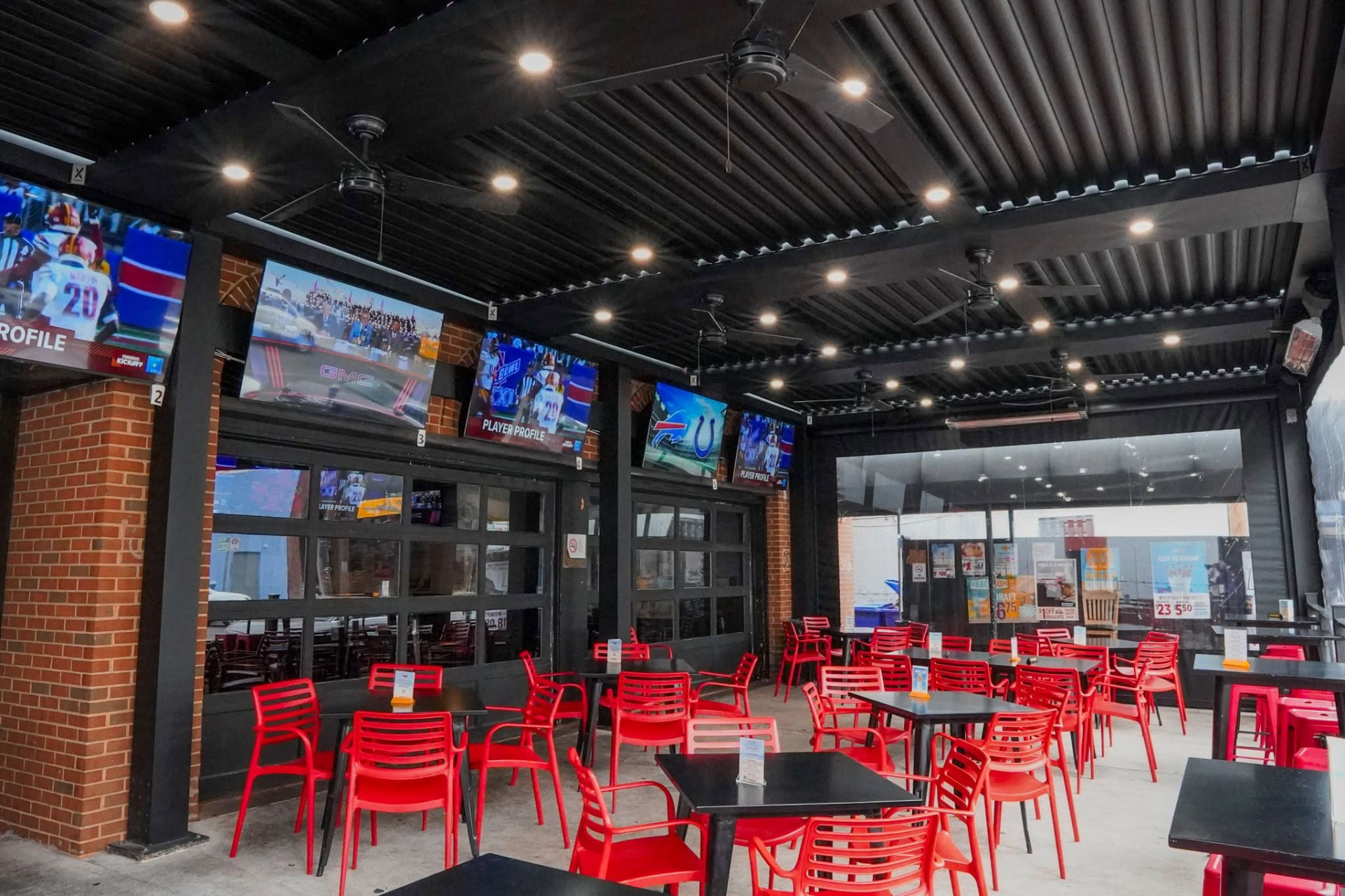 Covered patio at Caddies on Cordell with red chairs, tables, and televisions
